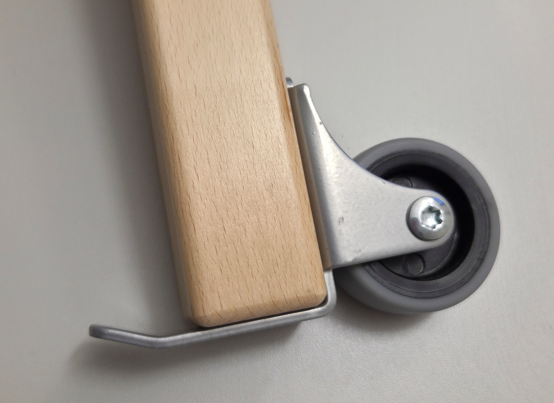 Eine Nahaufnahme der „Rollendiscount“-Rolle mit Kippschutz, Rad-Ø 50 mm mit weicher Lauffläche und 2 Befestigungsbohrungen, montiert an einem Holzfuß mit Metallhalterung – ideal für Stuhlrollen in Pflegeeinrichtungen.