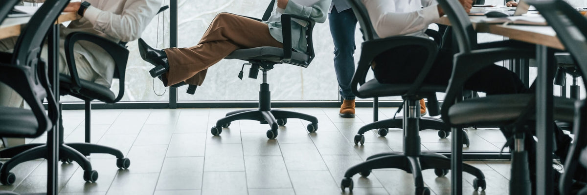 Menschen, die in einem modernen Büro sitzen und stehen, aufgenommen aus einem niedrigen Blickwinkel in der Nähe von Bürostühlen auf Rollen.